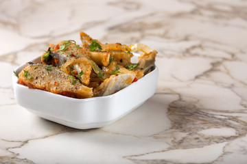 Marinated herring fish with onion and tomato sauce in white bowl