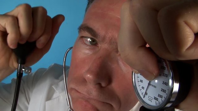 A fisheye view of a man who appears to be a doctor  holding a blood pressure gauge.