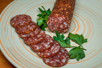 Smoked sausage salami sliced on a plate with greens