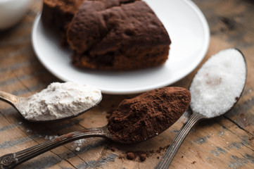 Cake, flour, sugar, cocoa, milk and eggs on a wooden table. Ingredients for cooking.