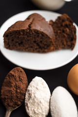 Cake, flour, sugar, cocoa, milk and eggs on a black background. Ingredients for cooking.