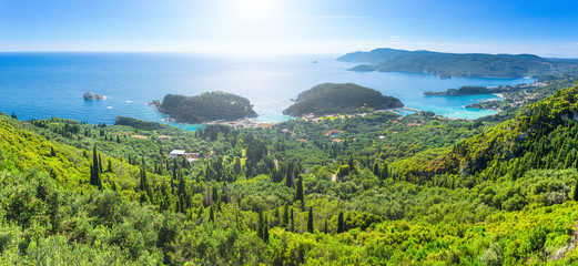 Beautiful summer panoramic seascape. View of the coastline into the sea bays with crystal clear azure water. In the backlight sunbeam light. Paleokastrica. Corfu. Ionian archipelago. Greece. - obrazy, fototapety, plakaty