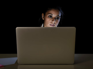 young business woman or student girl working in darkness on laptop computer late at night looking concentrated