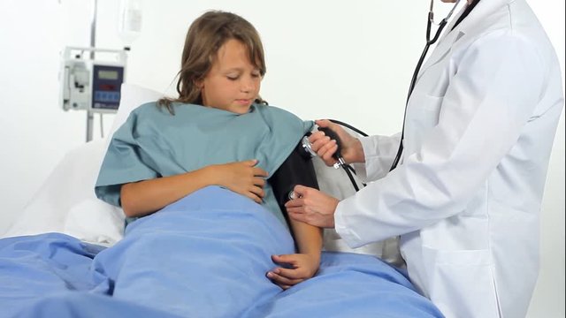 A doctor or nurse in a hospital  checking a young patient’s blood pressure.