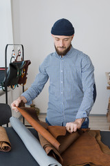 Fototapeta na wymiar Man designer sorting leather in a workshop