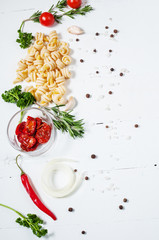 Background with pasta, tomatoes cherry and herb on white wooden table. Place for text.