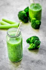 Green vegetable smoothie in glass at gray background