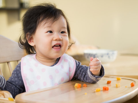 baby girl eating  vegetable first time at home