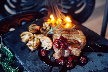 pork steak with mushrooms and cherry sauce over vintage background on fire