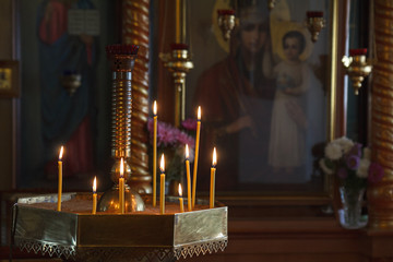 Burning candles to the icon of the mother of God. In the Orthodox Church during the service candles. In a dark room.