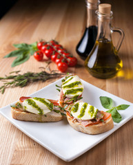 bruschetta on a white plate on a wooden table, surrounded by decor