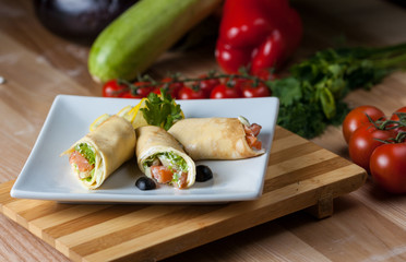 plate of pancakes with marinated salmon on a wooden table, surrounded by decor