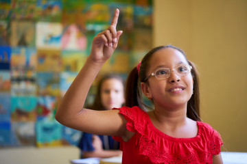 Female Student Raising Hand During Test In Class At School