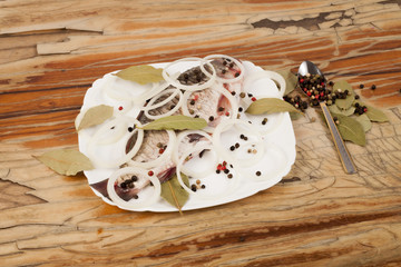 Fish on a white plate on a wooden background with seasoning