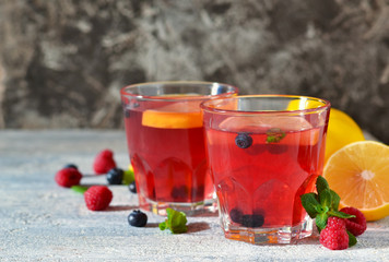 Cold berry drink with lemon and mint on a concrete background