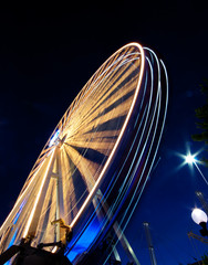 A vibrant Ferris wheel with vivid colours, photographed outdoor with long exposure at twilight....