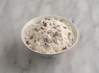 Bowl of blueberry muffin mix on a gray marble cutting board.