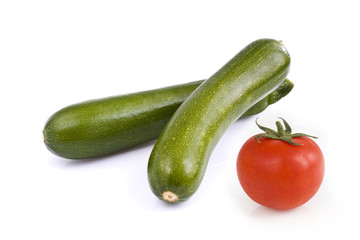 Two green zucchini and a cherry tomato, isolated on white background. Still-life picture taken in studio with soft-box.