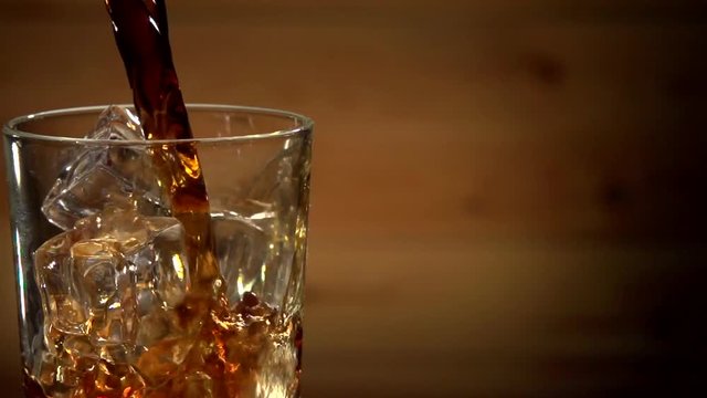 Cola Pouring Into Glass With Ice Cubes. Close Up Soda Soft Drink. Slow motion 240 fps. 
