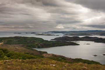 Fototapeta na wymiar Assynt Peninsula, Scotland - June 7, 2012: Under dark cloudy sky aerial view on Loch Ardhair with intrusion of the ocean in the wild landscape of hills, mountains, bare land, small and larger islands.