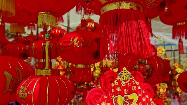 NHA TRANG, KHANH HOA/VIETNAM - JANUARY 26 2017: Wind shakes hung up large painted in gold red Chinese lanterns on street market before Vietnamese new year TET on January 26 in Nha Trang