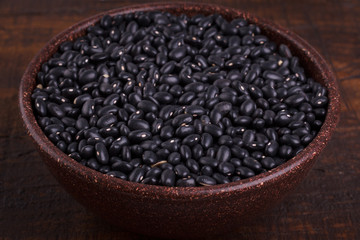 Black beans in scoop on wooden background