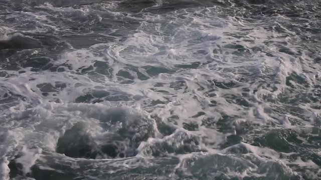 Vaiven de las Olas del mar batiendo en la costa rocosa y produciendo espuma
