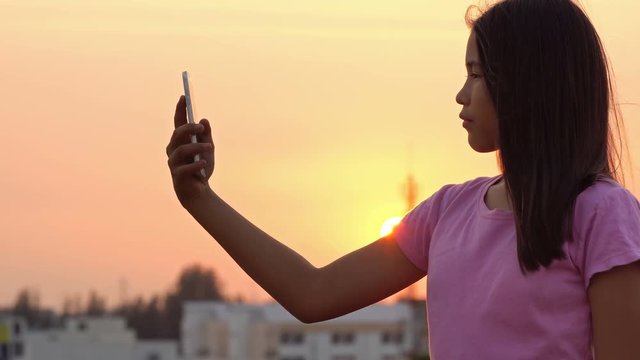 Asian women taking selfie outdoors at sunset light
