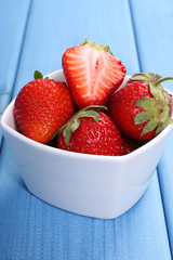 Fresh strawberries in glass bowl on blue boards, healthy dessert