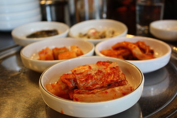 Korean appetizer at a restaurant served in white small dishes with closeup on kimchi