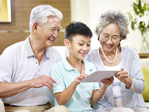 asian grand parents and grand child using tablet at home