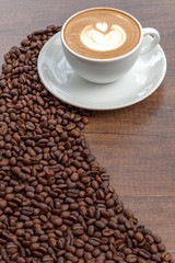 Coffee cup of latte art with coffee beans on wooden background