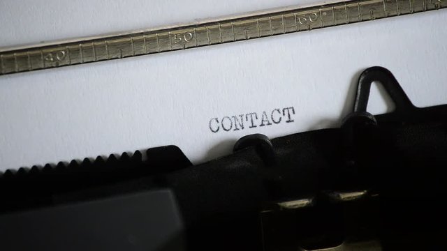 Typing the word CONTACT with an old manual typewriter