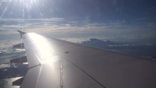 View through an airplane window on the mountains, sky and clouds. Rocky Mountains through Airplane Window. Aerial view Clouds and sky as seen through window of an aircraft. 4K video. Aerial footage