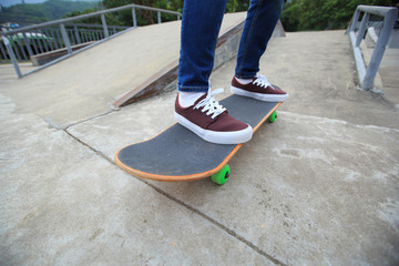 young skateboarder legs riding skateboard at skatepark