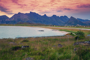 Fjord at sunset, wild beach in evening. Silhouette of rocks against colorful sunset sky. Lofoten, Norway