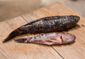 closeup fresh died fish for cooking food on wooden chop board  in the kitchen.