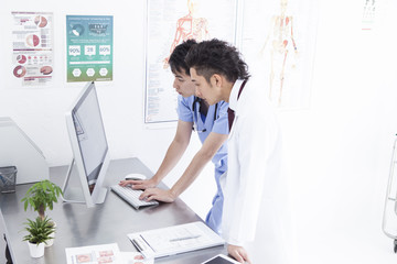 Two doctors are talking while watching a personal computer