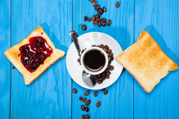Breakfast, toast, jam with berries and a cup of coffee on a wooden blue background