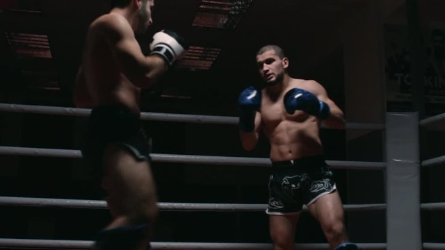 Two muscular mixed martial arts athletes fighting in the ring in slow motion