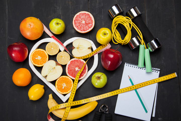 Diet plan, fruits and centimeter on a black background