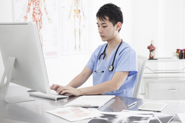 A young male doctor is using a personal computer