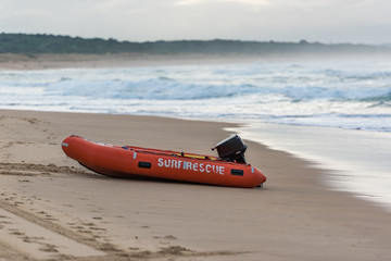 Bright orange surf saver boat on sandy beach shore