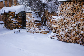 Pile of logs with snow in village countryside