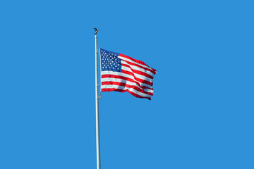 waving USA flag on pole against blue sky