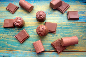 pieces of chocolate and chocolate candies on a blue wooden background
