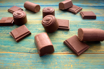 pieces of chocolate and chocolate candies on a blue wooden background