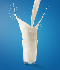 Pouring milk into glass on blue background