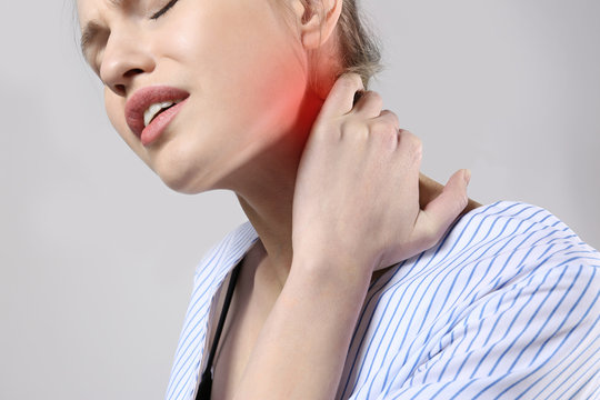 Young woman suffering from neck pain on gray background. Health care concept