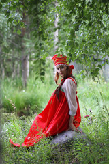 Slav in traditional dress is sitting in nature